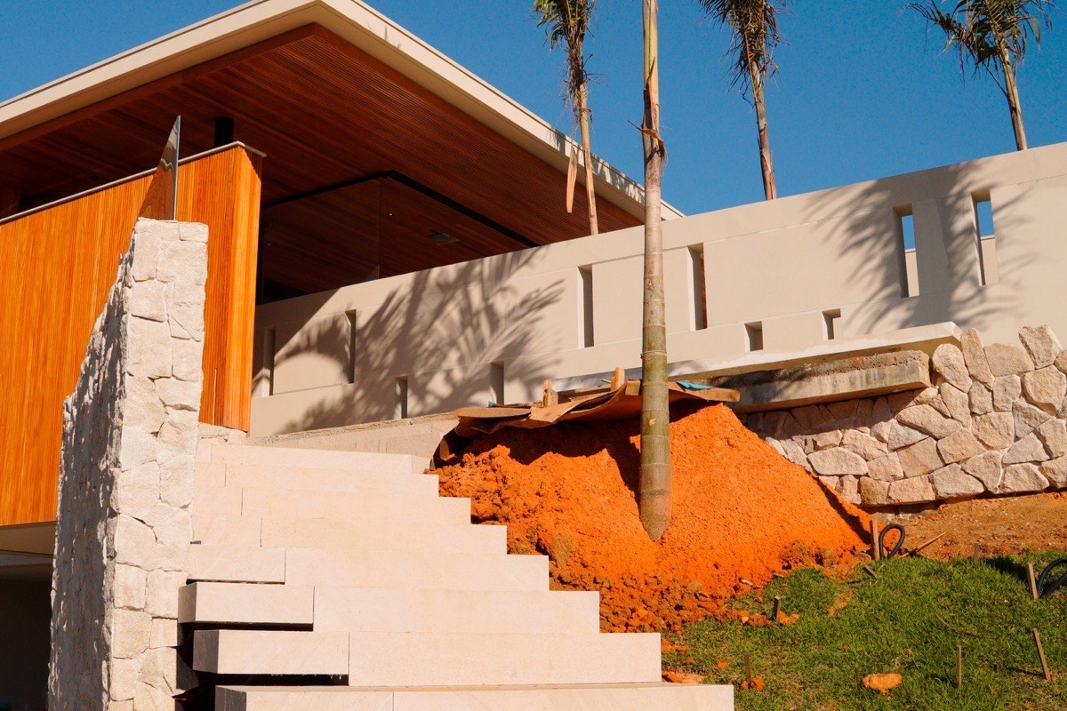 Obra de casa de alto padrão em fase de acabamento em Criciúma, com estrutura de concreto aparente e equipe de engenharia acompanhando o andamento